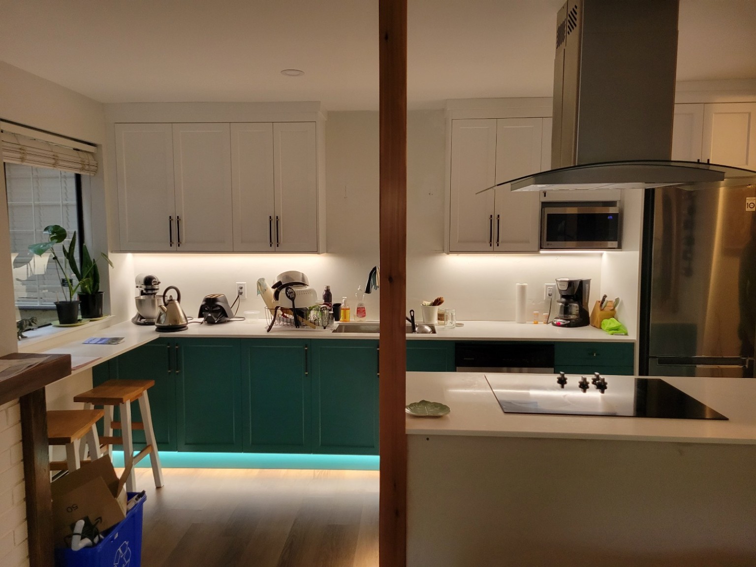 Kitchen with white upper cabinets, green lower cabinets, under-cabinet lights and illuminated toe-kick
